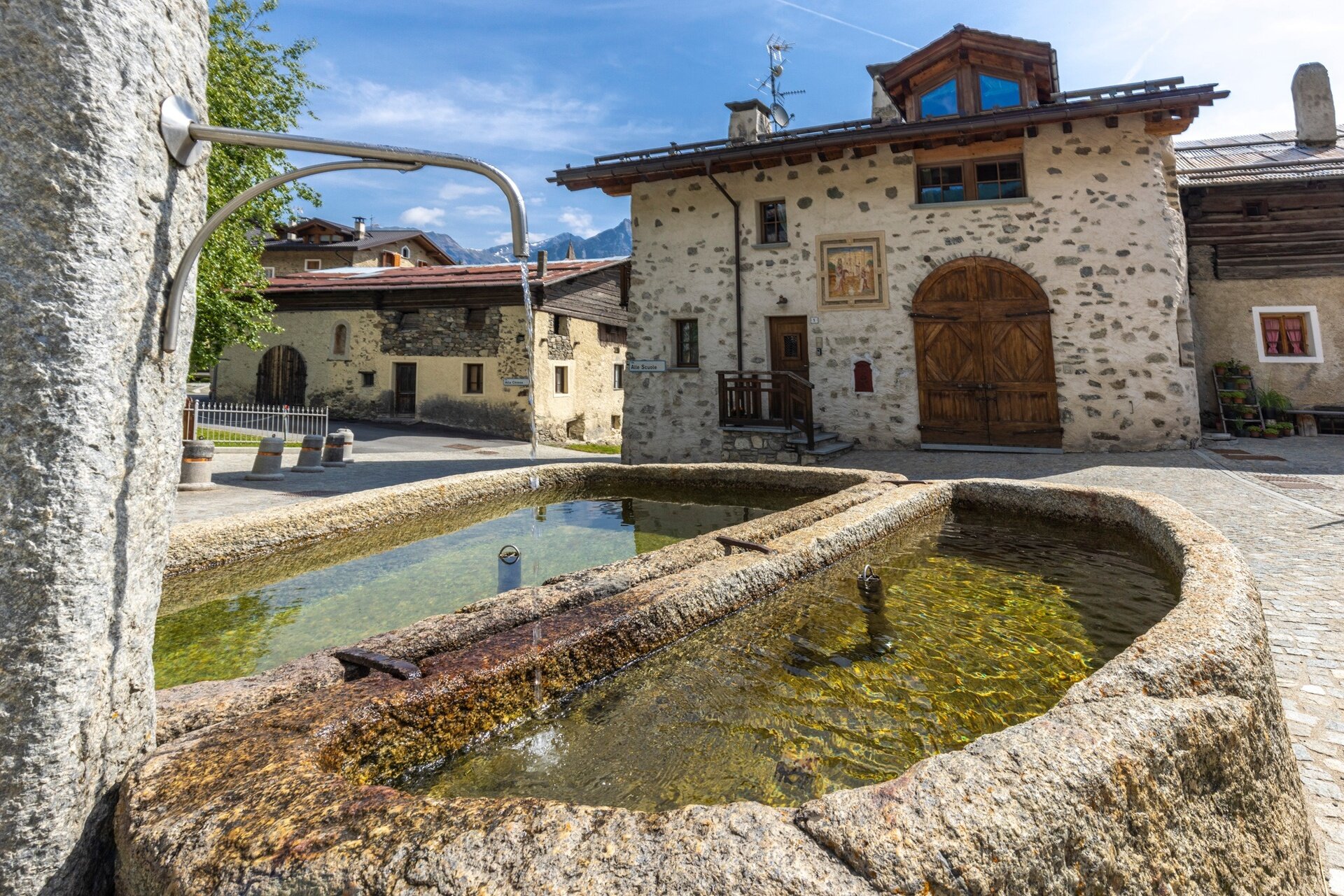 Apparition scene frescoed on an old house near a beautiful stone fountain.